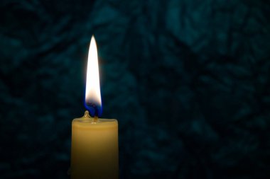 Tek sarı mum, arka planda tek başına yanıyor. Kavramsal görüntü, ücretsiz kopya alanı ile barışı, aşkı, umudu veya sabrı simgeler