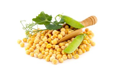 Tahta bir kepçe ve yeşil yapraklı yeşil bezelyelerden dökülen kuru sarı bezelyeler.