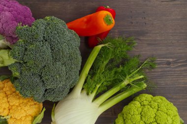 Telif alanı olan ahşap üzerinde sağlıklı taze sebzelerin kırsal sınırı. Tepeden bakıldığında renkli karnabahar tarlaları, brokoli ve kırmızı biberler de dahil.