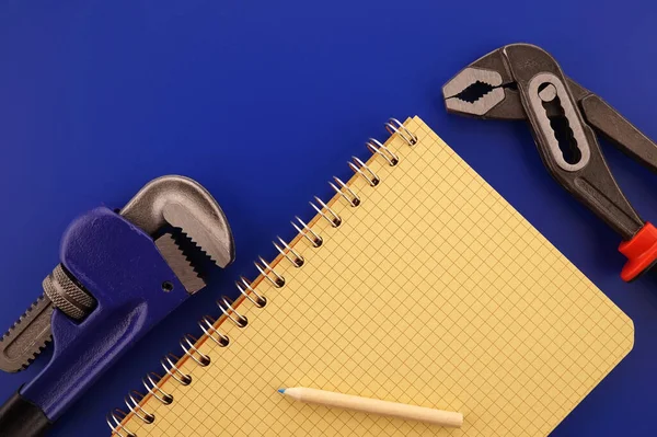 Yenileme, üretim, imalat, inşaat veya onarım, iki farklı anahtar ve defterin mavi ve kırmızı temalı düzenlenmesiyle düz konsept.