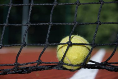 Tenis topu ağda. Top tenis ağında, tenis sahnesinde siyah ağ ve sarı top.