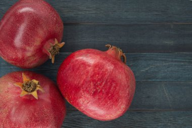 Mavi ahşap arka planda üç olgun nar meyvesi, fotokopi alanı ile üst manzara.