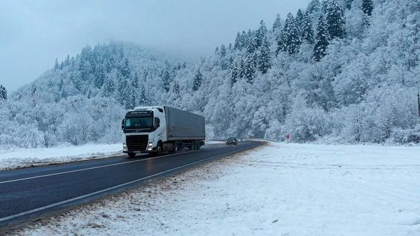 Muhteşem hava aracı görüntüsü: Güzel kış ormanlarında yol boyunca giden bir kamyon tamamen beyaz karla kaplı..