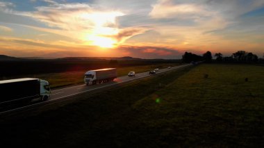 İnanılmaz Hava Aracı Görünümü: Otomobiller ve Yarı Kamyonlar Yoldan Geçiyor. Sunset Summer saati: Blue Sky, Red Sun. Güneş ışınları yolu aydınlatıyor..