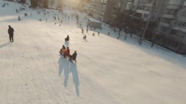 Lviv, Ukrayna - 01.20.2022: FPV Drone Sinematik Çekim: Mutlu çocuklar kayaktan kayıyor. Güneşli gündüz.