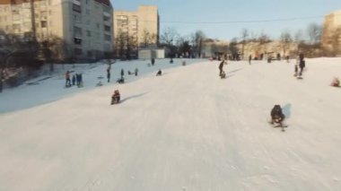 Lviv, Ukrayna - 01.20.2022: FPV Drone Sinematik Çekim: Mutlu çocuklar kayaktan kayıyor. Güneşli gündüz.