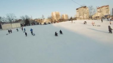 FPV Drone Sinematik Çekimi: Mutlu çocuklar kayaktan kayıyor. Güneşli gündüz.