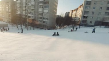 FPV Drone Sinematik Çekimi: Mutlu çocuklar kayaktan kayıyor. Güneşli gündüz.