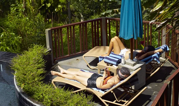 Frauen sonnen sich neben Pool — Stockfoto