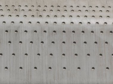 Gri beton duvarda yuvarlak delikler.
