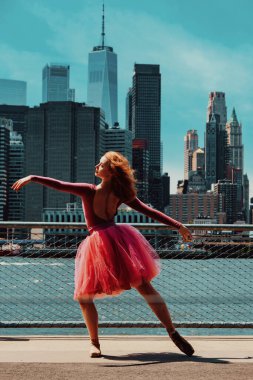 Kızıl saçlı genç kız şehir caddesinde poz veriyor. 