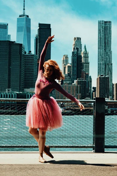 Kızıl saçlı genç kız şehir caddesinde poz veriyor. 