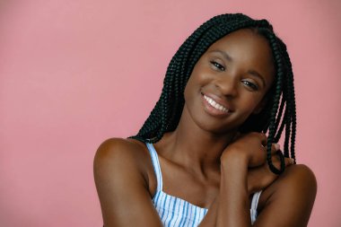 Pembe arka planda poz veren çekici Afrikalı genç modelin portresi. 