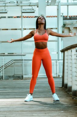 Güzel genç bayan koşucu dışarıda spor kıyafetiyle esniyor. 