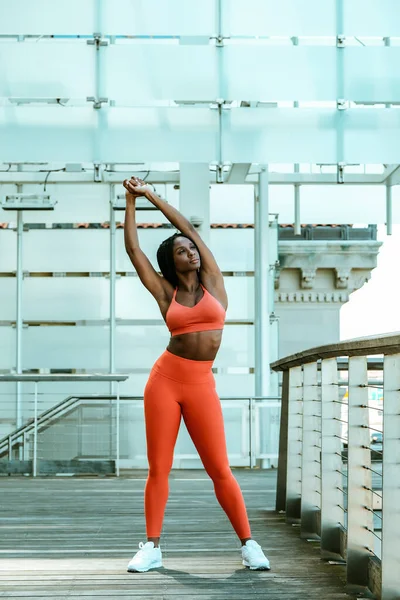 Güzel genç bayan koşucu dışarıda spor kıyafetiyle esniyor. 