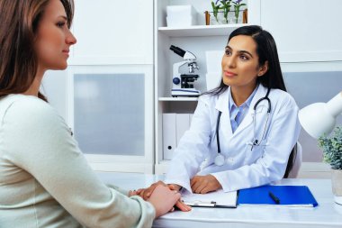 Genç bayan hasta, modern klinik tıp merkezinde hoş bir kadın doktoru ziyaret ediyor.