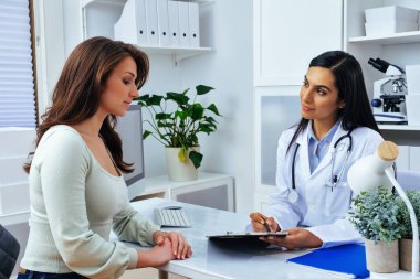 Genç bayan hasta, modern klinik tıp merkezinde hoş bir kadın doktoru ziyaret ediyor.