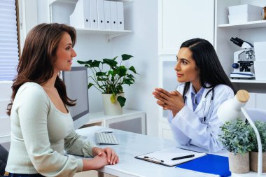 Genç bayan hasta, modern klinik tıp merkezinde hoş bir kadın doktoru ziyaret ediyor.