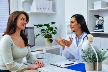 Genç bayan hasta, modern klinik tıp merkezinde hoş bir kadın doktoru ziyaret ediyor.