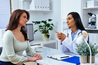 Genç bayan hasta, modern klinik tıp merkezinde hoş bir kadın doktoru ziyaret ediyor.