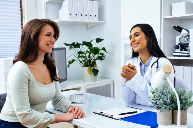 Genç bayan hasta, modern klinik tıp merkezinde hoş bir kadın doktoru ziyaret ediyor.