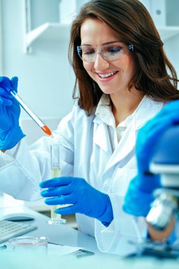 Laboratuvarda deney tüpüyle araştırma yapan genç ve güzel bir bilim adamı ya da araştırmacı.