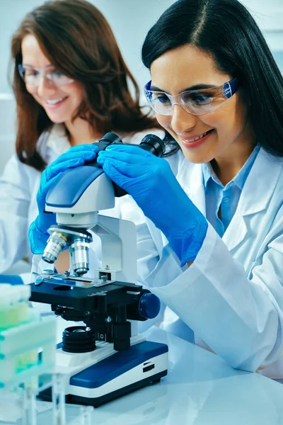 Joven Científica Usando Microscopio Mientras Colega Trabaja Segundo Plano — Foto de Stock