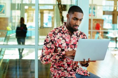 Ofisinde dizüstü bilgisayarı olan Afro-Amerikan bir adam.