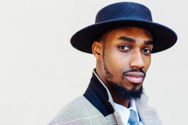 Beyaz arka planda şapka ve takım elbiseli yakışıklı bir Afro-Amerikan 'ın portresi.