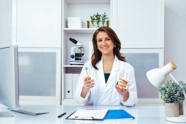 Gülümseyen kadın doktor insan çenesi ve diş modellemesi gösteriyor 