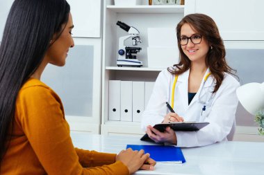 Kadın doktor hastanedeki hastaya reçete yazıyor..