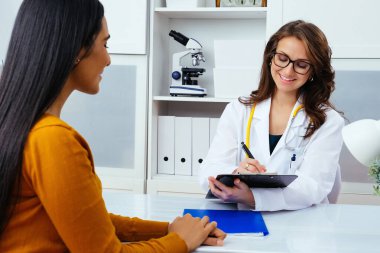 Kadın doktor hastanedeki hastaya reçete yazıyor..