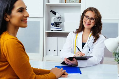 Kadın doktor hastanedeki hastaya reçete yazıyor..