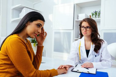 Kadın doktor hastasıyla hastanede konuşuyor.