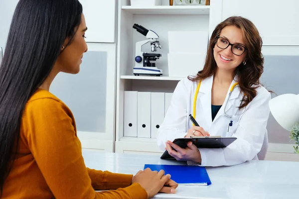 Kadın doktor hastanedeki hastaya reçete yazıyor..