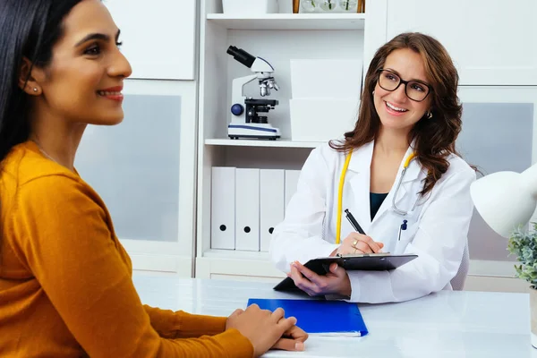 Kadın doktor hastanedeki hastaya reçete yazıyor..