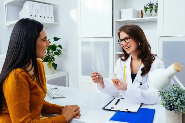 Corona virüsü aşısını ve şırıngayı elinde tutan kadın doktor COVID-19 enfeksiyonunu önlemek için kullanıyor.