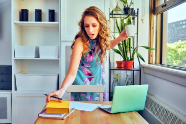 young woman with laptop and cup of coffee studying at home