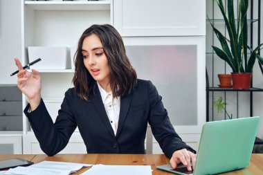 Laptop ve belgelerle çalışan genç iş kadını. 