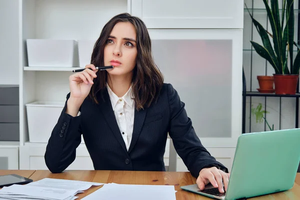 Laptop ve belgelerle çalışan genç iş kadını. 