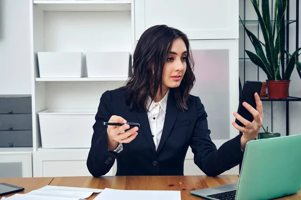 Ofiste cep telefonuyla çalışan genç bir iş kadını.