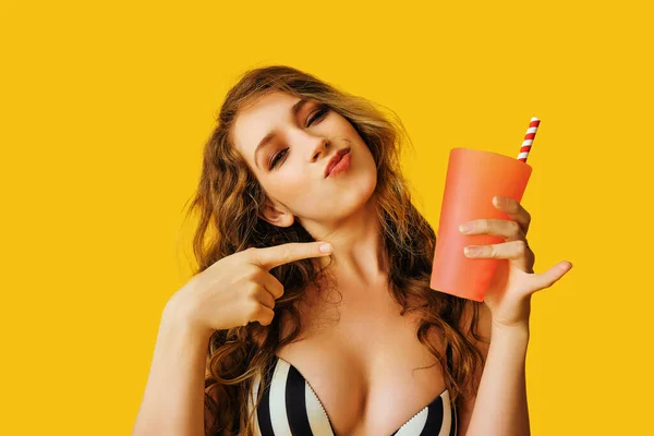 beautiful young woman with cocktail on yellow background