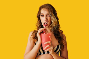 Renkli bir arka planda elinde turuncu bir kokteyl tutan mayolu güzel bir kız. yüksek kaliteli fotoğraf