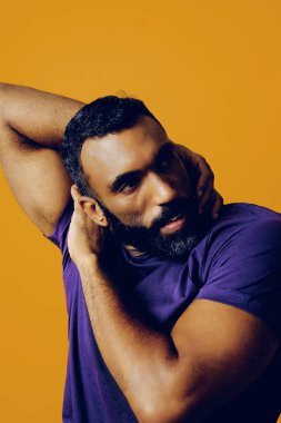 Sarı arka planda sakallı ve bıyıklı yakışıklı bir genç.