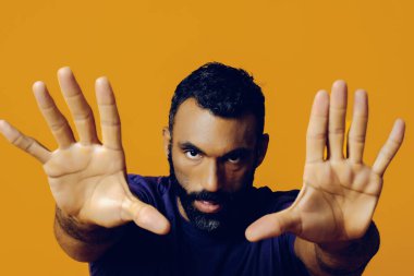 Sarı arka planda siyah kazaklı ve sakallı bir gencin portresi.