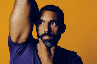 Sarı arka planda sakallı ve bıyıklı yakışıklı bir gencin portresi.