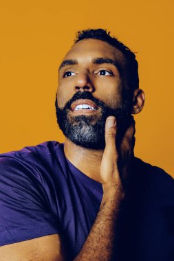 Sarı arka planda sakallı ve bıyıklı yakışıklı bir gencin portresi.