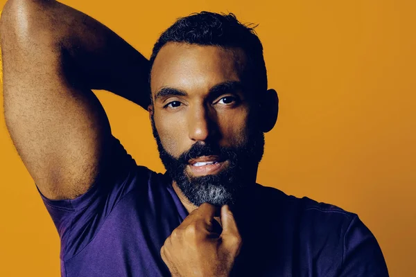 Stüdyoda sakallı ve bıyıklı yakışıklı genç adam poz veriyor.