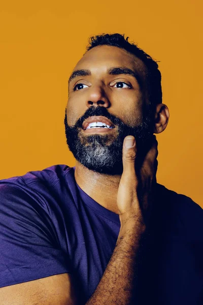 Sarı arka planda sakallı ve bıyıklı yakışıklı bir gencin portresi.