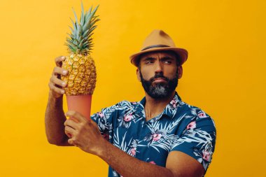 Hawai tişörtü ve ananas ve cam kaplı şapka giyen yakışıklı Afro-Amerikan bir adam.